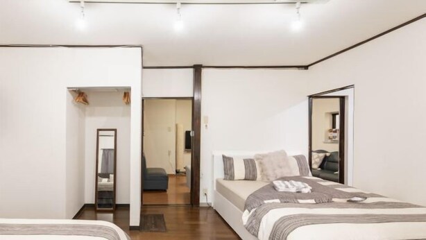 Un dormitorio con cama, espejo y puerta que da a otra habitación.