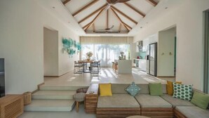 A spacious living area with a high ceiling, wooden beams, a sofa set, a dining table, and a kitchen area. - Villa Allamanda 3 Bdrm Best Location Bangtao Beach VVPHU88 (Phuket)