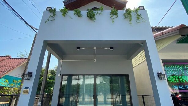 Un bâtiment à la façade blanche, avec un auvent vert et un panneau lumineux qui indique : « ACHETEZ-EN UN, RECEVEZ-EN UN GRATUIT SUR TOUS LES ARTICLES ».