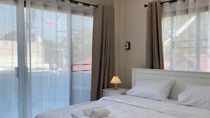 Une chambre d’hôtel avec un lit, des rideaux, une table de chevet avec une lampe et une vue par la fenêtre.