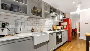 Eine moderne Küche mit grauen Schränken, einem roten Kühlschrank und einem Holzboden.