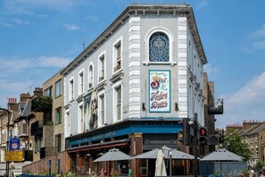 Ein Gebäude mit einem großen Bogenfenster, einem Schild mit der Aufschrift 'The Old Market House' und einer blauen Markise.