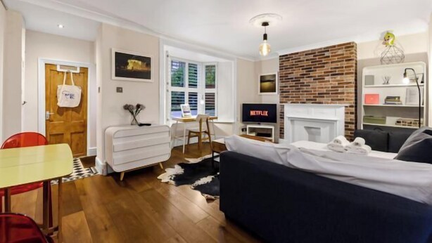 Ein modernes Wohnzimmer mit Kamin, Fernseher und Essbereich mit Tisch und Stühlen.