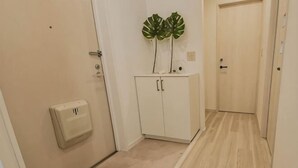 A hallway with a white cabinet, a plant, and a door. - GLOCE Guest House Nagisa 5 mins from the station (Zushi)