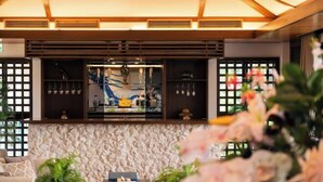A modern interior with a stone wall, a bar area with glassware, and a sofa. - Amano Terrace (Onna)