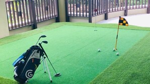 A miniature golf course with a green artificial turf, a golf bag, and a flag. - Amano Terrace (Onna)
