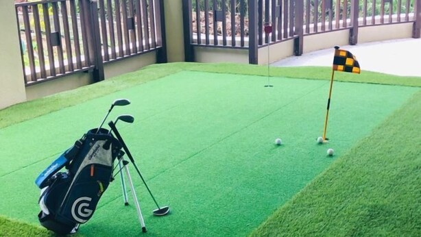 A miniature golf course with a green artificial turf, a golf bag, and a flag. - Amano Terrace (Onna)