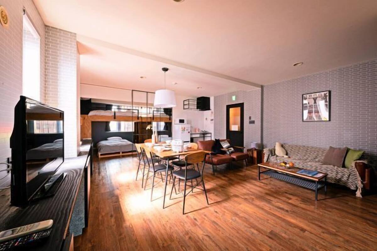 A modern hotel room with a bunk bed, a dining area, a sofa, and a coffee table.