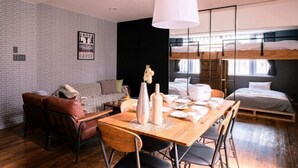 Et moderne værelse med spisebord, stole, sofa, køjeseng og en hængende lampe.