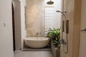A modern bathroom with a freestanding bathtub, a shower, and a decorative wall panel. - Sueño Villa Seminyak (Bali)