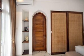 A room with a wooden door, a shelf with decorative items, and a sliding door. - Sueño Villa Seminyak (Bali)