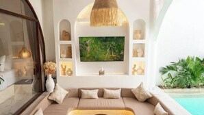 A modern living room with a beige sofa, a coffee table, and a flat-screen TV mounted on the wall. - Sueño Villa Seminyak (Bali)