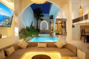 A pool area with a sofa, a television, and a hanging light fixture. - Sueño Villa Seminyak (Bali)
