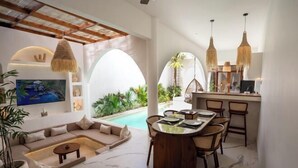 A modern interior with a pool, a dining area, and a living room with a sofa and a coffee table. - Sueño Villa Seminyak (Bali)