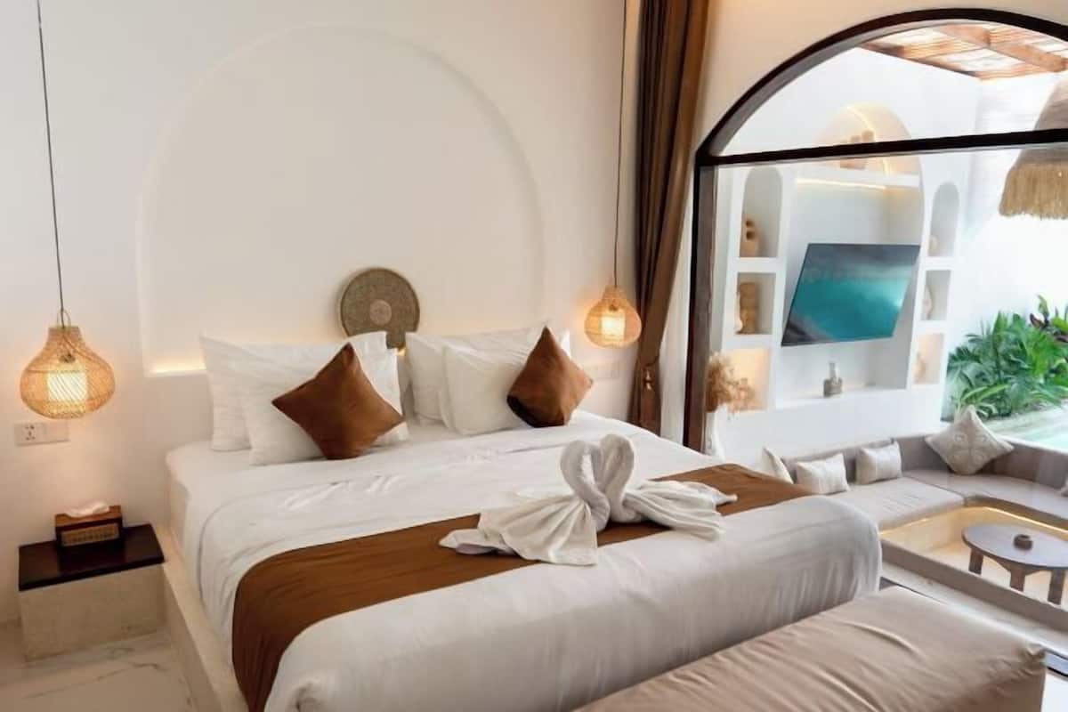 A hotel room with a bed, a sofa, a small table, and a large window with a view.