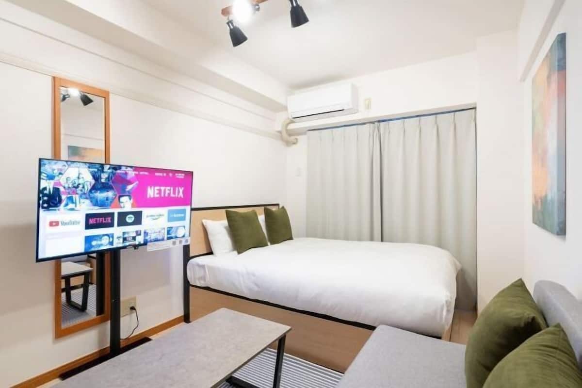 A hotel room with a bed, a TV displaying Netflix, and a window with curtains.
