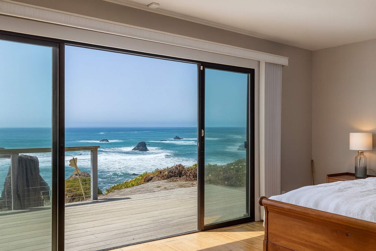 Une chambre dotée d’une grande porte-fenêtre coulissante donnant sur un balcon avec vue sur l’océan.