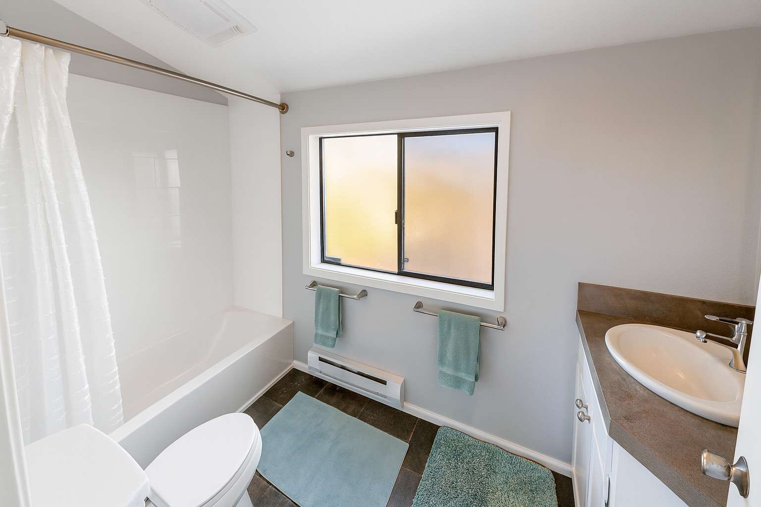 Een badkamer met een bad, toilet, wastafel en een raam met uitzicht.