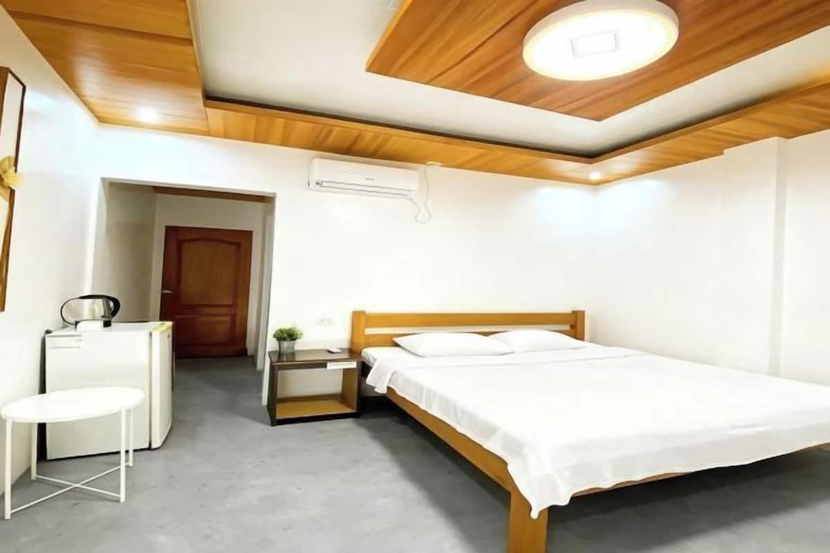 A bedroom with a wooden ceiling, a bed, a desk, and a chair.