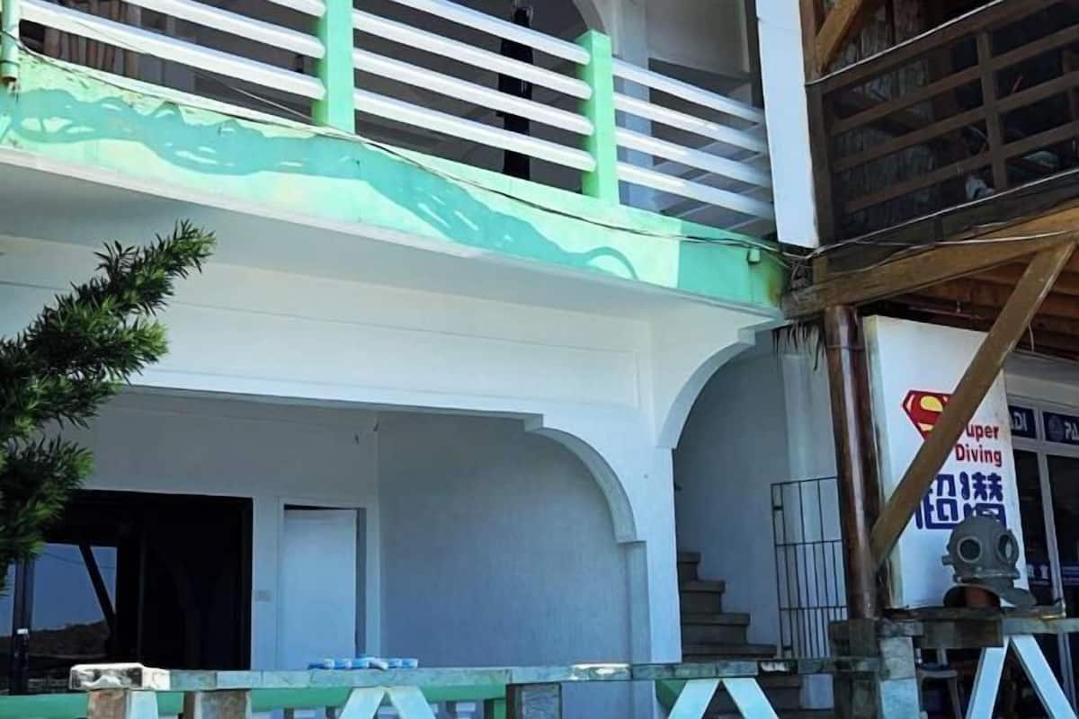 A multi-story building with a green awning, a staircase, and a sign for 'Super Diving'.