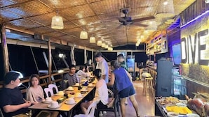 A restaurant with a high ceiling, hanging lights, and a counter with food items. - Super diving and tinas reef divers (Puerto Galera)