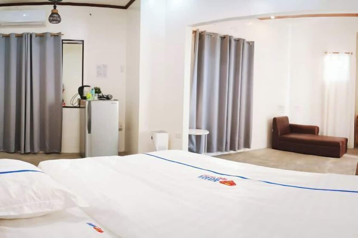 A hotel room with a bed, a small table, a chair, and a desk with a computer.