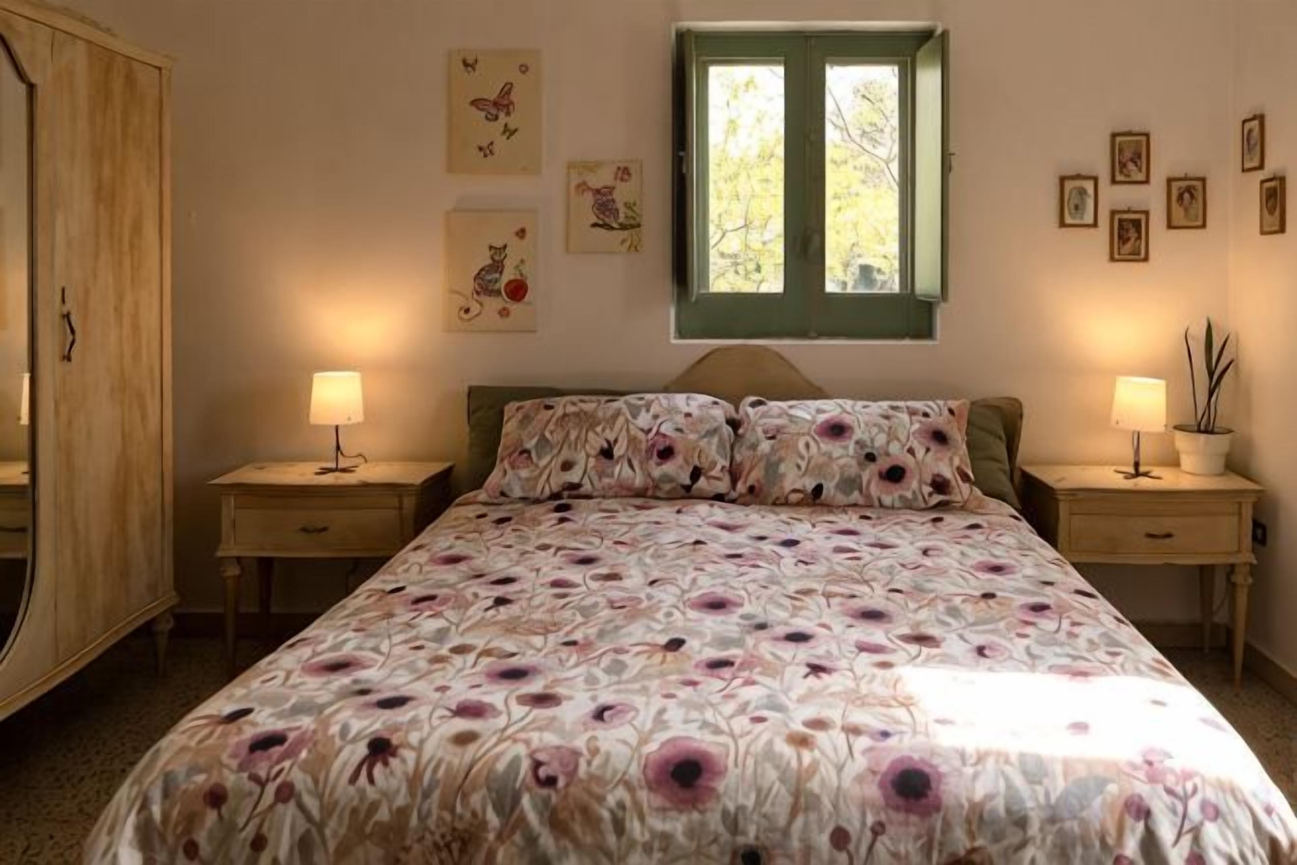 Una camera da letto con un letto, due comodini, una finestra e decorazioni alle pareti.