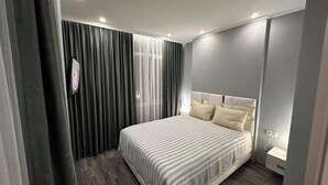 Une chambre à coucher moderne avec un lit, des rideaux et une table de chevet.