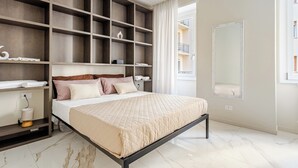Un dormitorio moderno con una cama grande, estanterías empotradas, una mesita de noche y un espejo amplio.