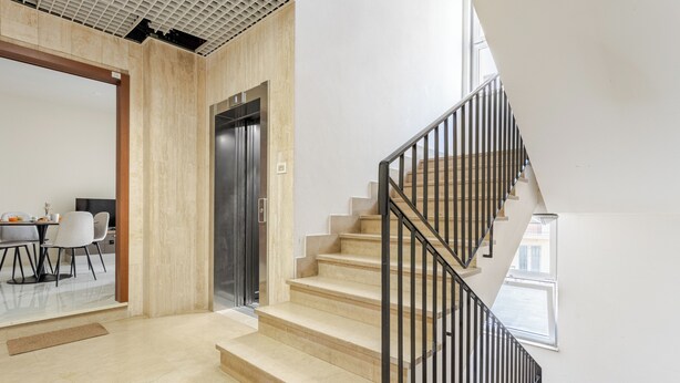 Un interior moderno con una escalera, una puerta y un comedor.
