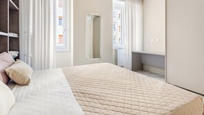 Un dormitorio con cama, armario, espejo y ventana.