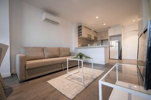 A modern living room with a sofa, a coffee table, and a kitchen area in the background. - A Chic 2BR, CBD Apartment Near Southern Cross (Melbourne)