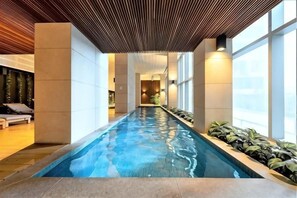 A long indoor swimming pool with a wooden ceiling, large windows, and potted plants along the sides. - A Chic 2BR, CBD Apartment Near Southern Cross (Melbourne)
