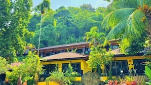 A yellow building surrounded by lush greenery and palm trees. - patong beautiful pool villa (Phuket)