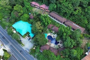 Vista aérea de una propiedad con piscina, una gran estructura tipo carpa azul y una carretera adyacente.