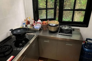A kitchen with a gas stove, a frying pan, a pressure cooker, and a gas cylinder. - patong beautiful pool villa (Phuket)