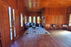 Una habitación amplia con pisos de madera, un conjunto de sofás, una mesa de centro y un jarrón decorativo.