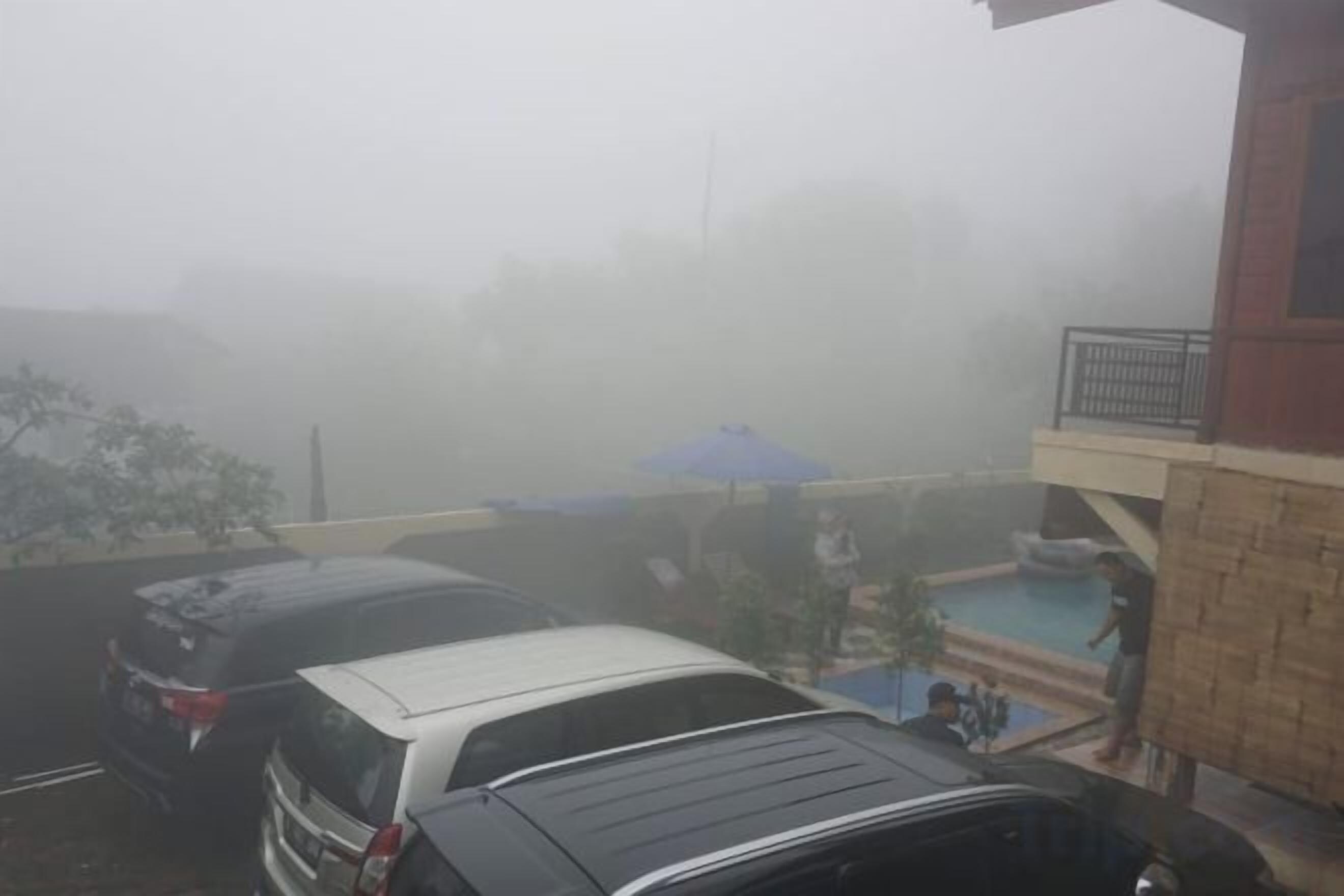 Un edificio con piscina, una zona cubierta y un coche estacionado en la entrada.