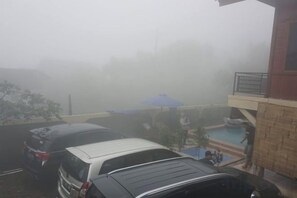 A building with a swimming pool, a covered area, and a car parked in front. - Villa Zoya 1 (Megamendung)