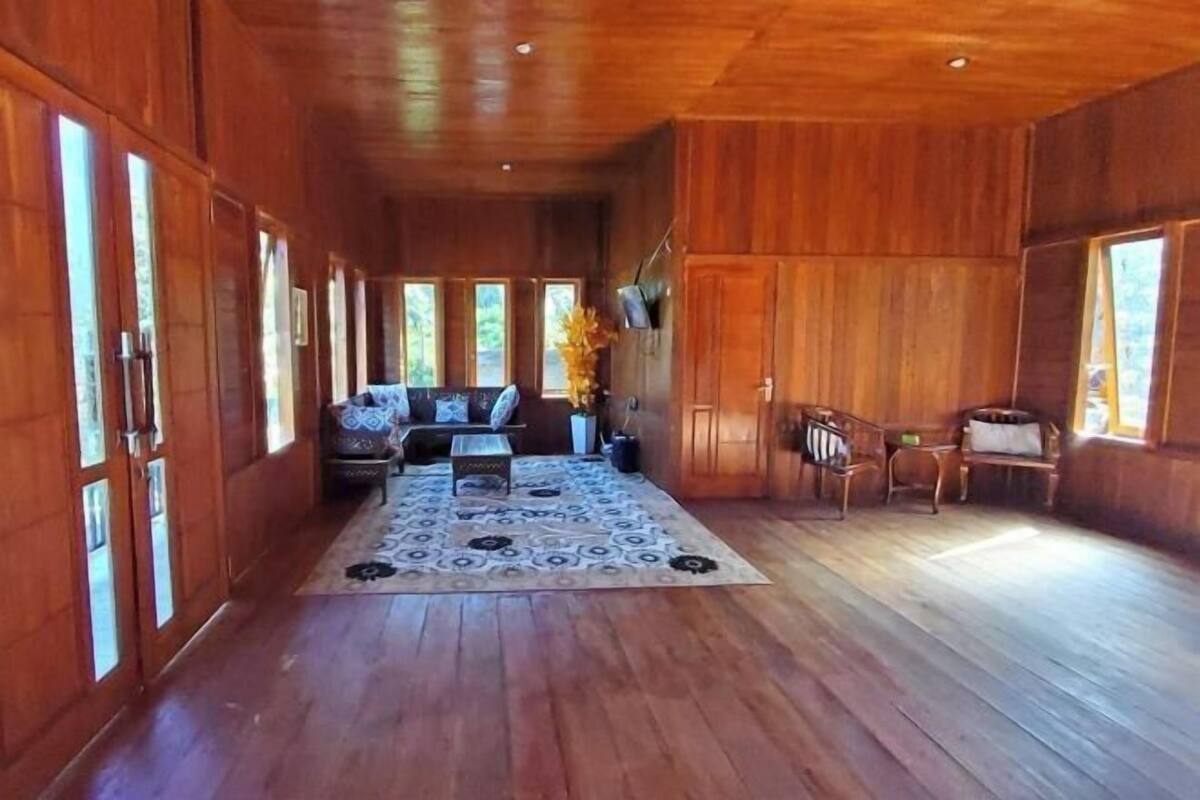 Un interior de madera con un sofá, sillas y una alfombra estampada.