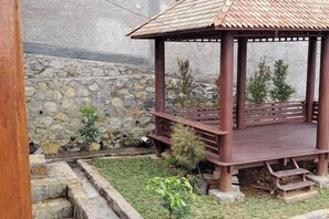 A wooden gazebo with a tiled roof, surrounded by a stone wall and small plants. - Villa Zoya 1 (Megamendung)
