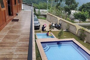 Una terraza de madera con piscina, una pequeña fuente de agua y una moto estacionada.