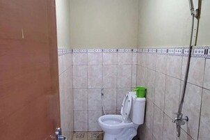 Un baño pequeño con inodoro, ducha y pared de azulejos.