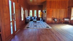 A wooden interior with a sofa set, a patterned rug, and a dining area. - Villa Zoya 1 (Megamendung)