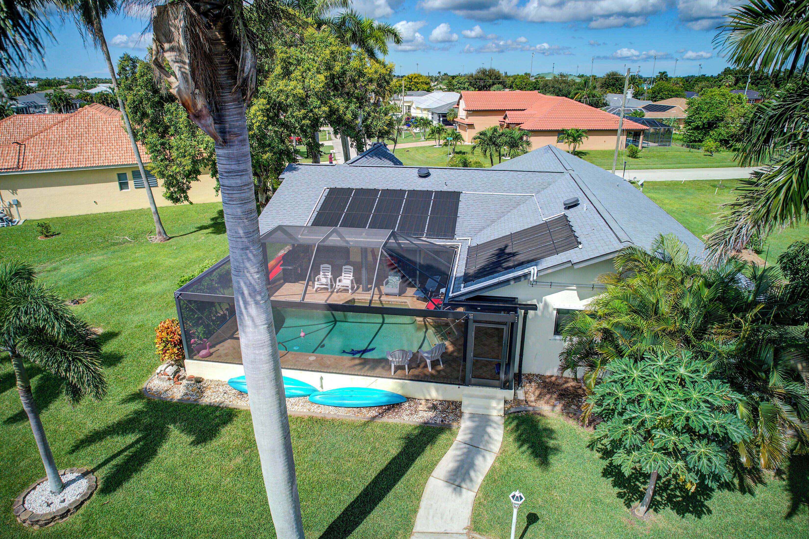 A house with a swimming pool, solar panels, and a covered patio area.