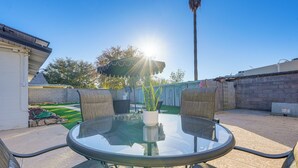 A round glass table with four chairs, a potted plant, and a patio umbrella. - Easy Walk to Dtwn Gilbert, Family-friendly Oasis! (Gilbert)