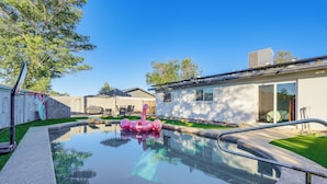 A swimming pool with a pink inflatable flamingo, a covered patio, and a modern house with a garage. - Easy Walk to Dtwn Gilbert, Family-friendly Oasis! (Gilbert)