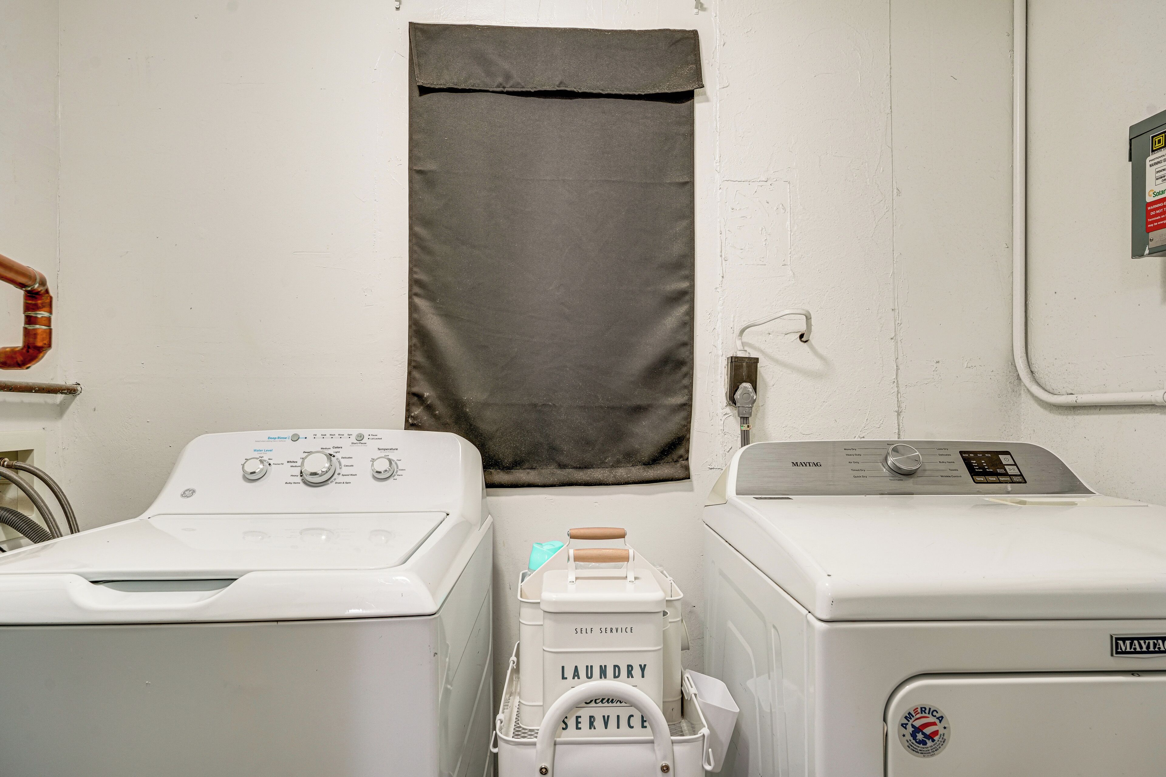 A laundry room with two washing machines, a dryer, and a water heater.