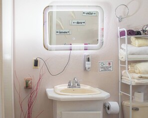 A bathroom with a sink, mirror, hand dryer, towel rack, and a sign prohibiting flushing feminine products. - Modern Holiday Apartment in Saint John's, Antigua (Potters Village)