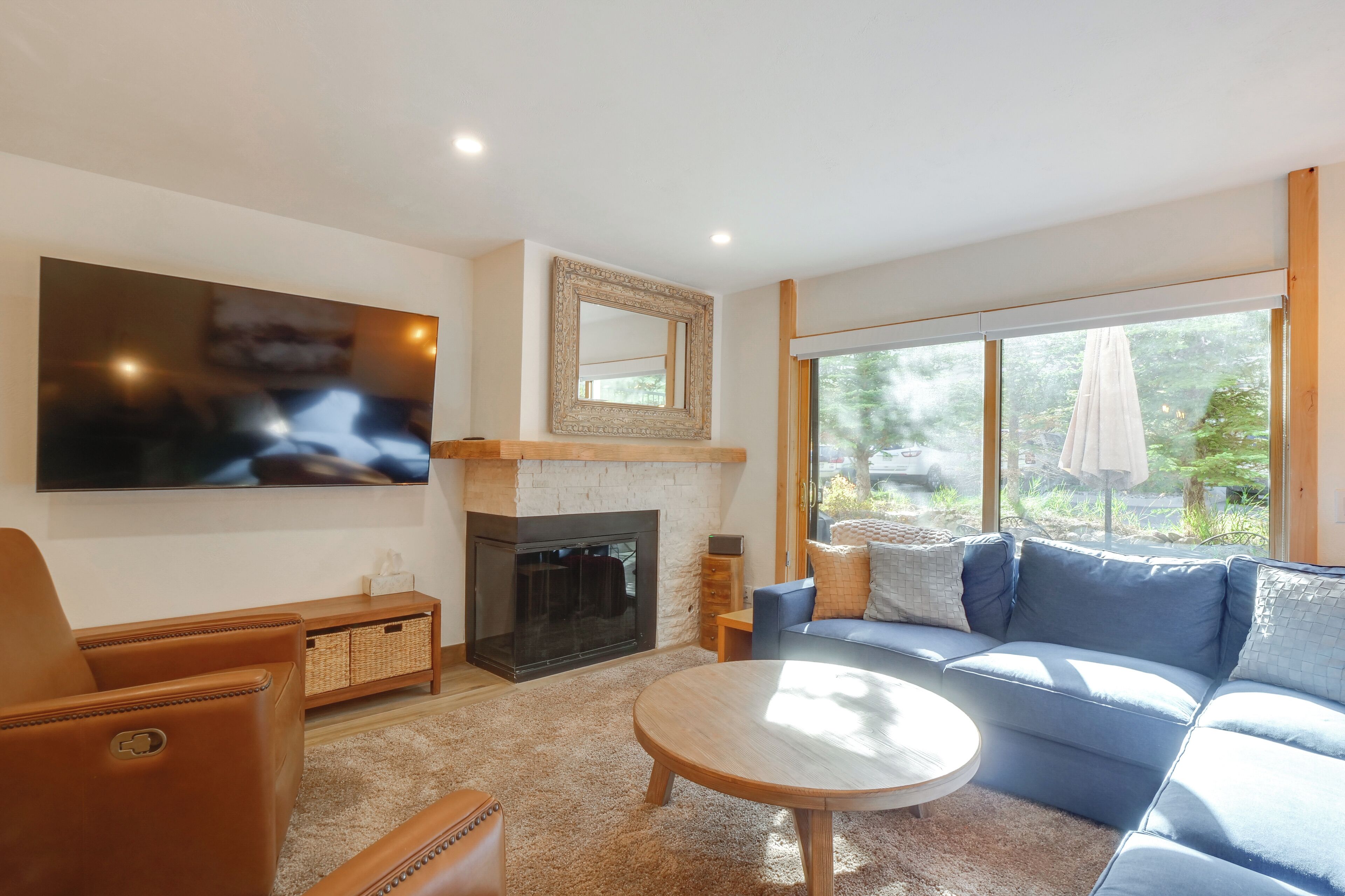 Una sala moderna con chimenea, un televisor de pantalla plana grande, un sofá azul y una mesa de centro redonda.